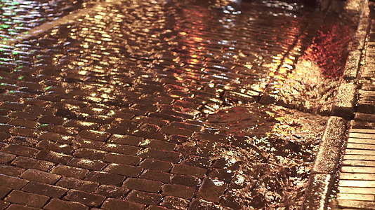 夜光反射沿古城街喷灌的雨水视频的预览图