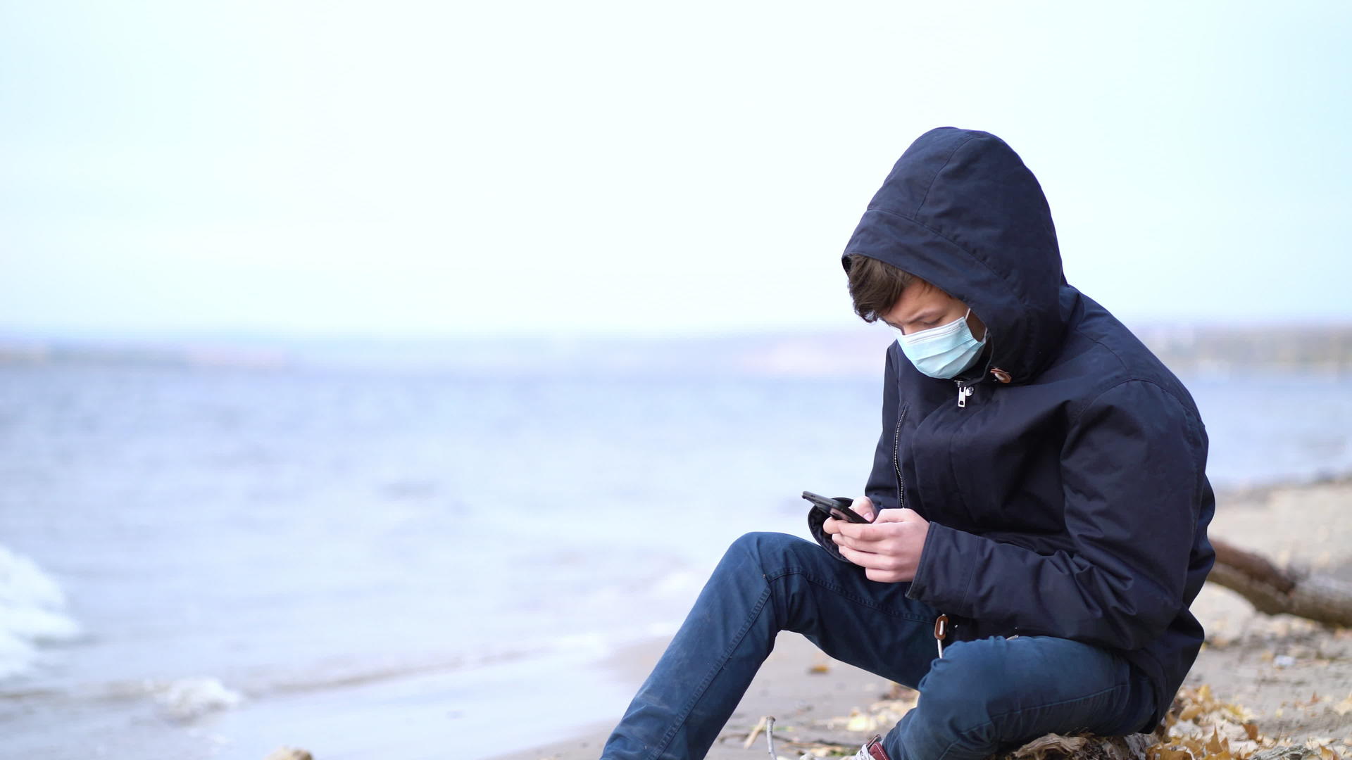 青少年在秋天的空海滩上玩网络电子游戏视频的预览图