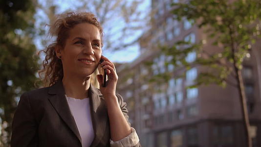 这位卷发迷人的女士在电话里有一个积极的对话视频的预览图