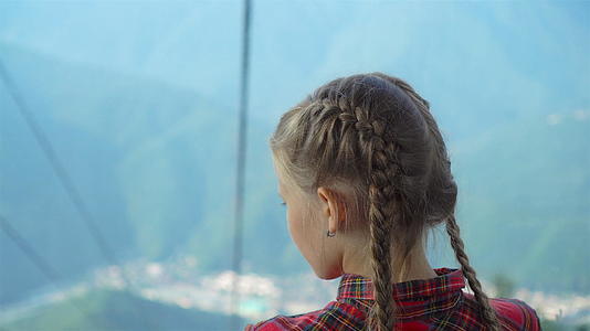 在美丽的风景背景下可爱快乐的小女孩在山上的缆车小屋里视频的预览图