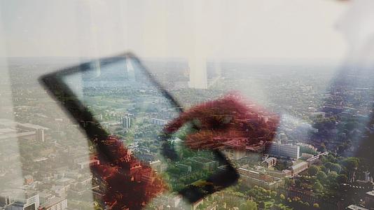一个人用平板电脑的反射和后面的城市风景视频的预览图