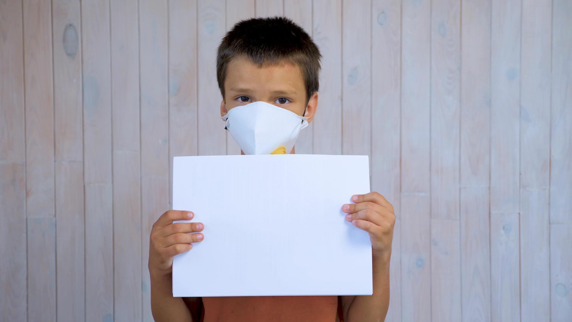 一个戴着医用口罩的拉丁男孩拿着一张纸视频的预览图