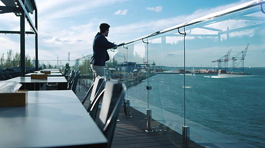 男士在屋顶露台休息欣赏海景视频的预览图