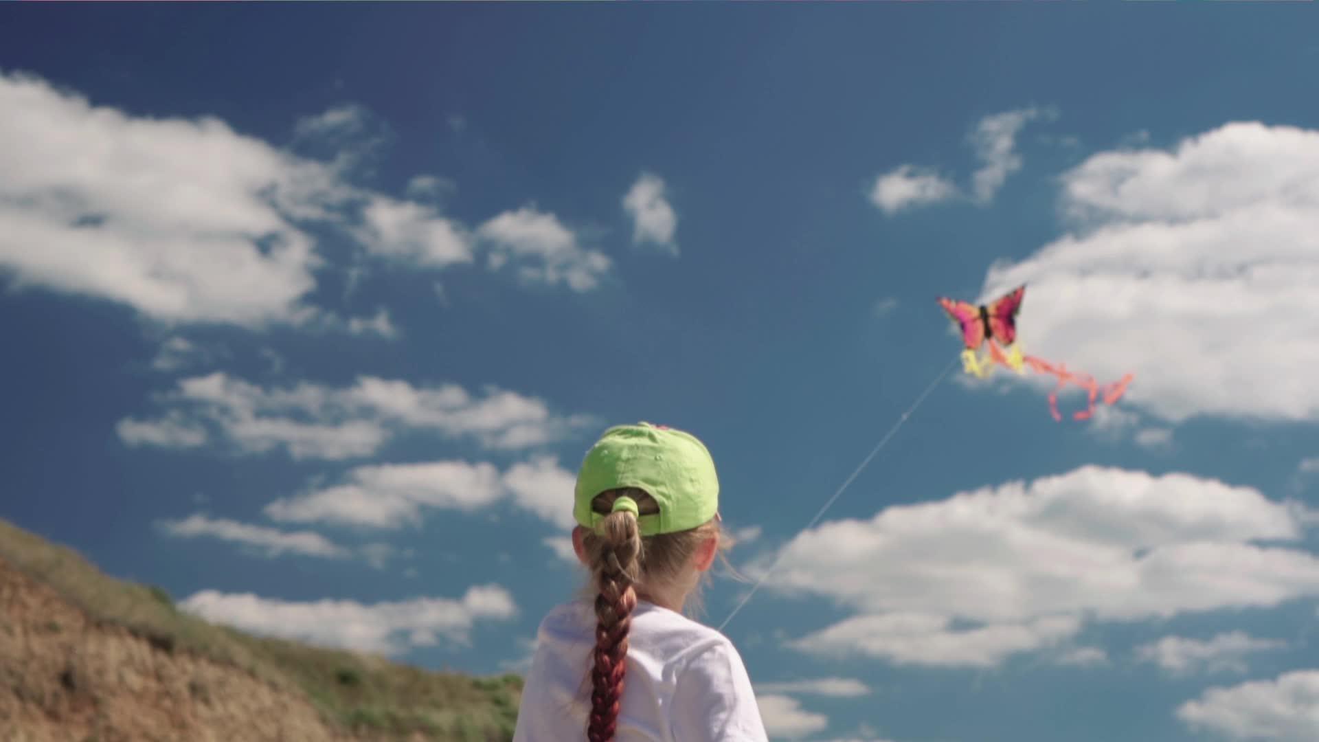 女孩在阳光明媚的夏天和风筝玩耍她控制风笛在风中慢慢地玩耍视频的预览图