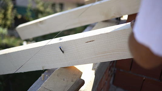 钉木板工人在屋顶安装时用锤子钉木板视频的预览图