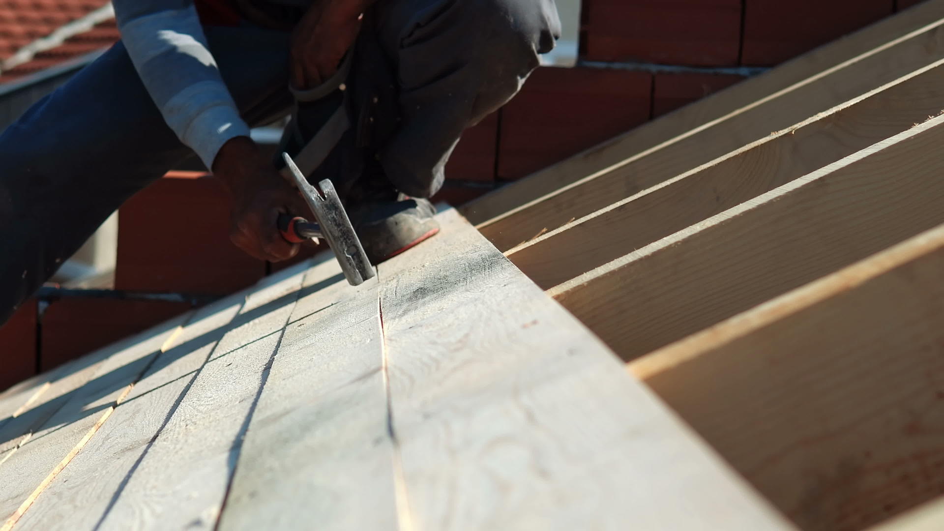 钉木板工人在屋顶安装时用锤子钉木板视频的预览图