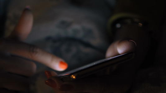 女性黑客在黑暗中使用智能手机放松娱乐和技术概念视频的预览图