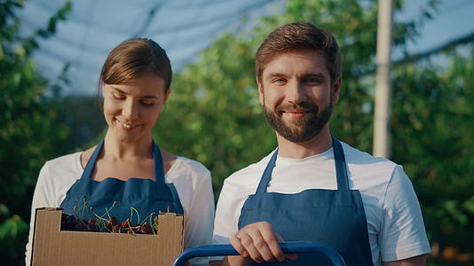 商业农民夫妇微笑着展示在果园里种植的樱桃视频的预览图