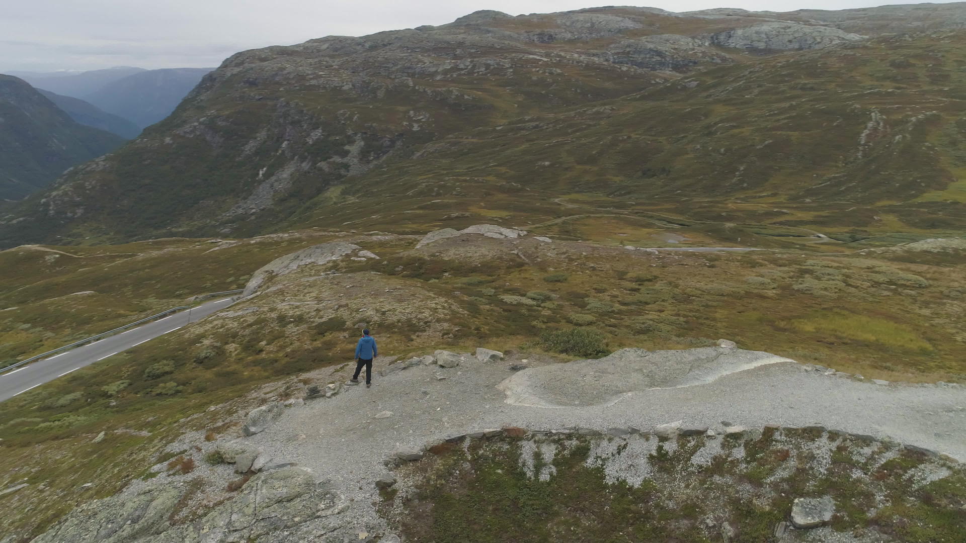 男人在夏天或秋天站在挪威山区鸟瞰图无人机正在绕道视频的预览图