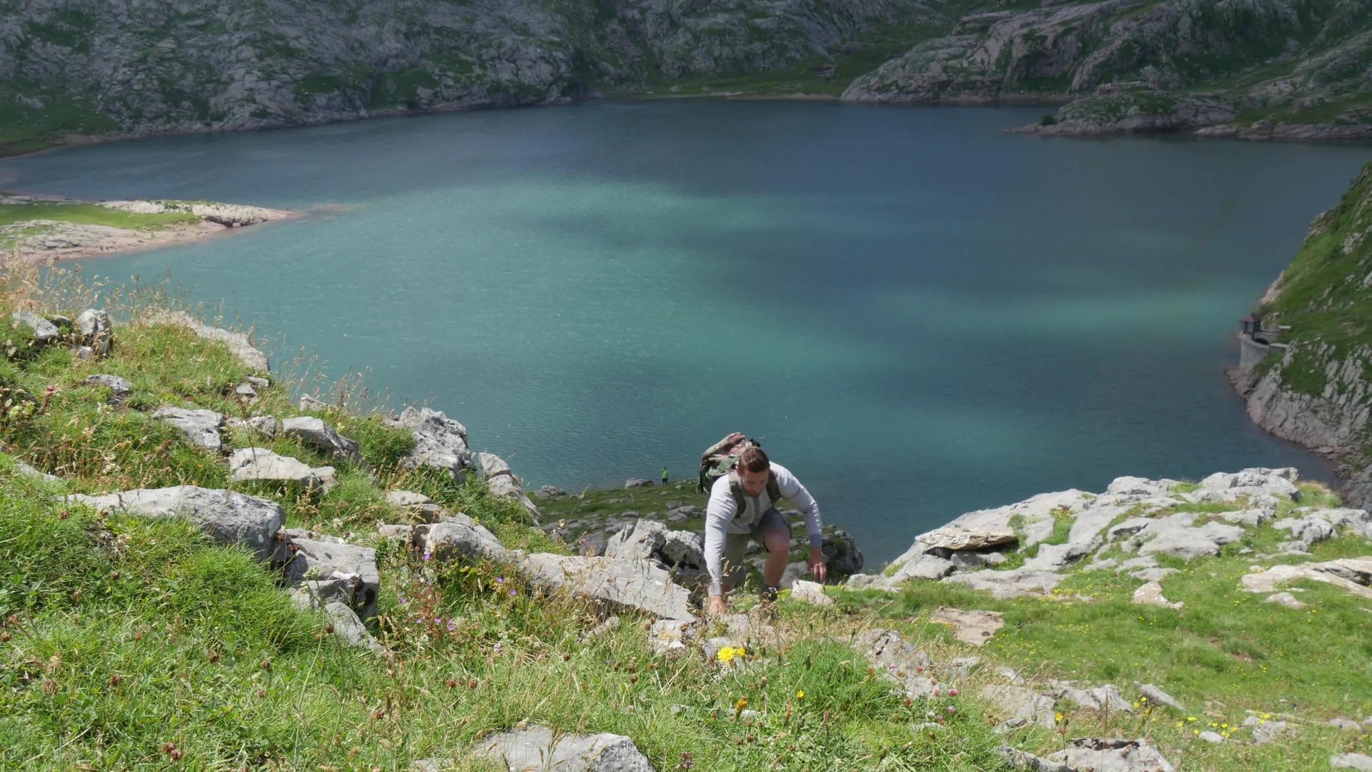 攀登山坡的登山者背景中的湖泊摇篮视频的预览图