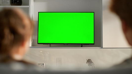 夫妇俩在客厅里放松地看着绿屏电视视频的预览图
