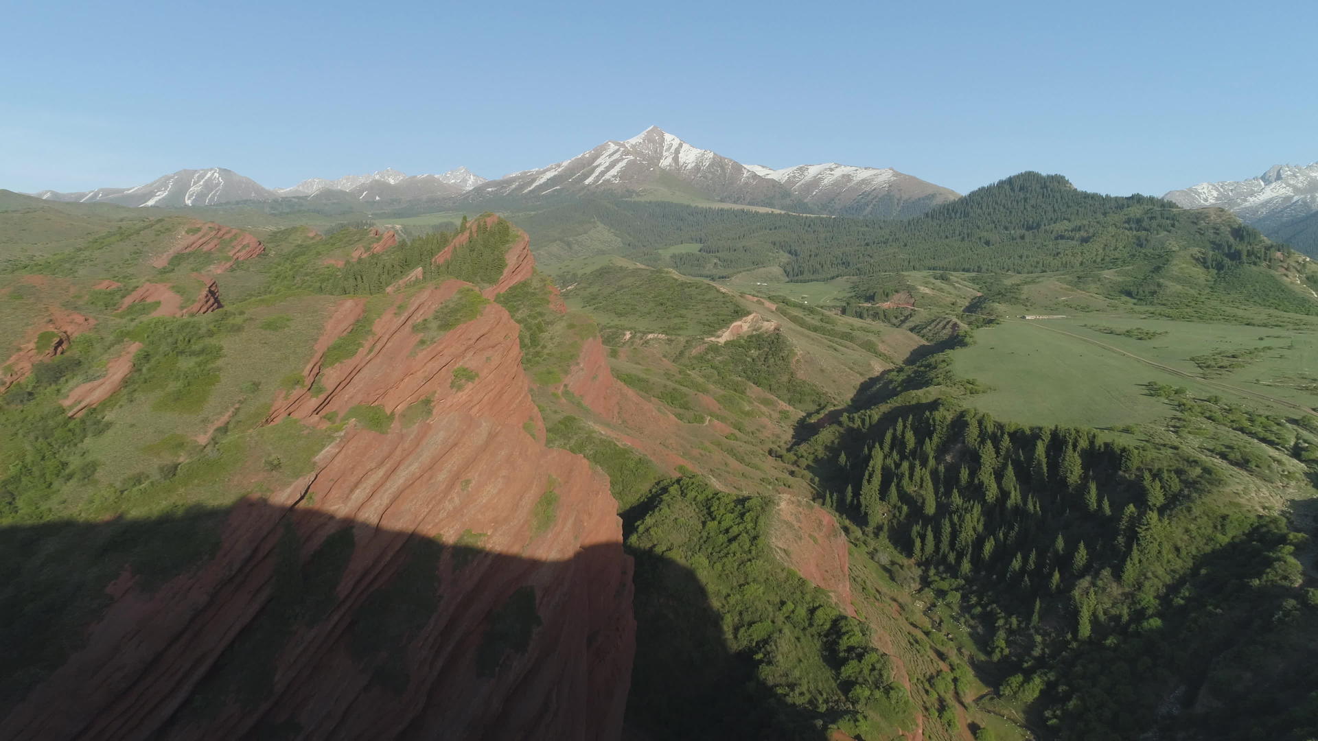 在红色岩石、隐形森林和山丘的背景下驾驶飞机在空中飞行视频的预览图