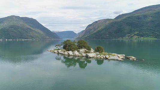 该岛在峡湾的背景是绿色的山脉挪威的卢斯特拉峡湾在水中反射视频的预览图