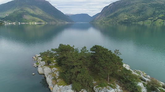 低空飞越峡湾岛屿的背景是绿色的山脉挪威的卢斯特拉峡湾在水中视频的预览图