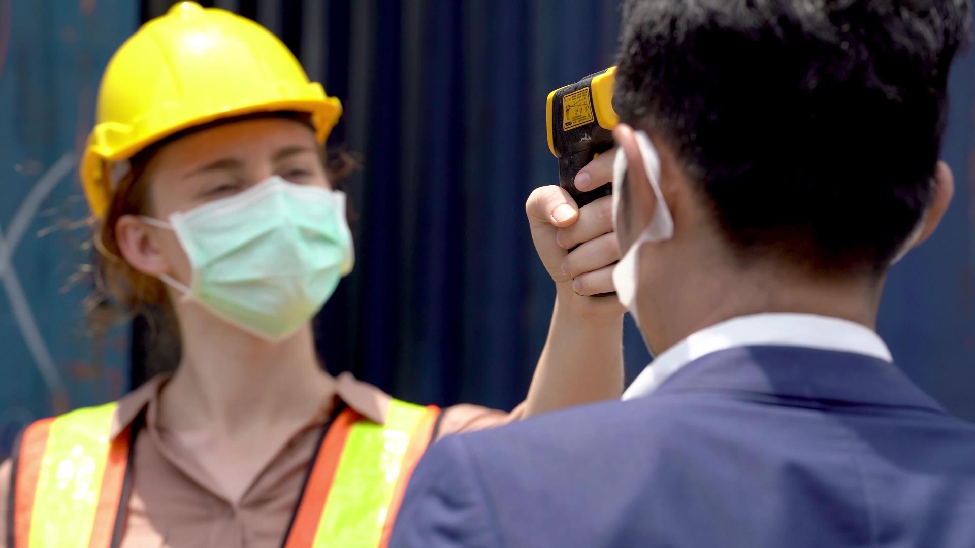 工厂工人戴口罩用温度计检查视频的预览图