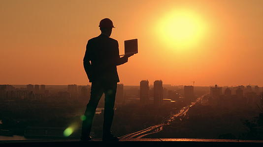 日出时商人戴着硬帽在城市风景中工作视频的预览图