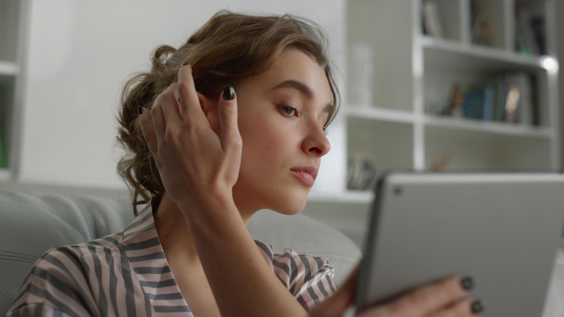 迷人的女人看着平板电脑屏幕用手摸着头发早上特写视频的预览图