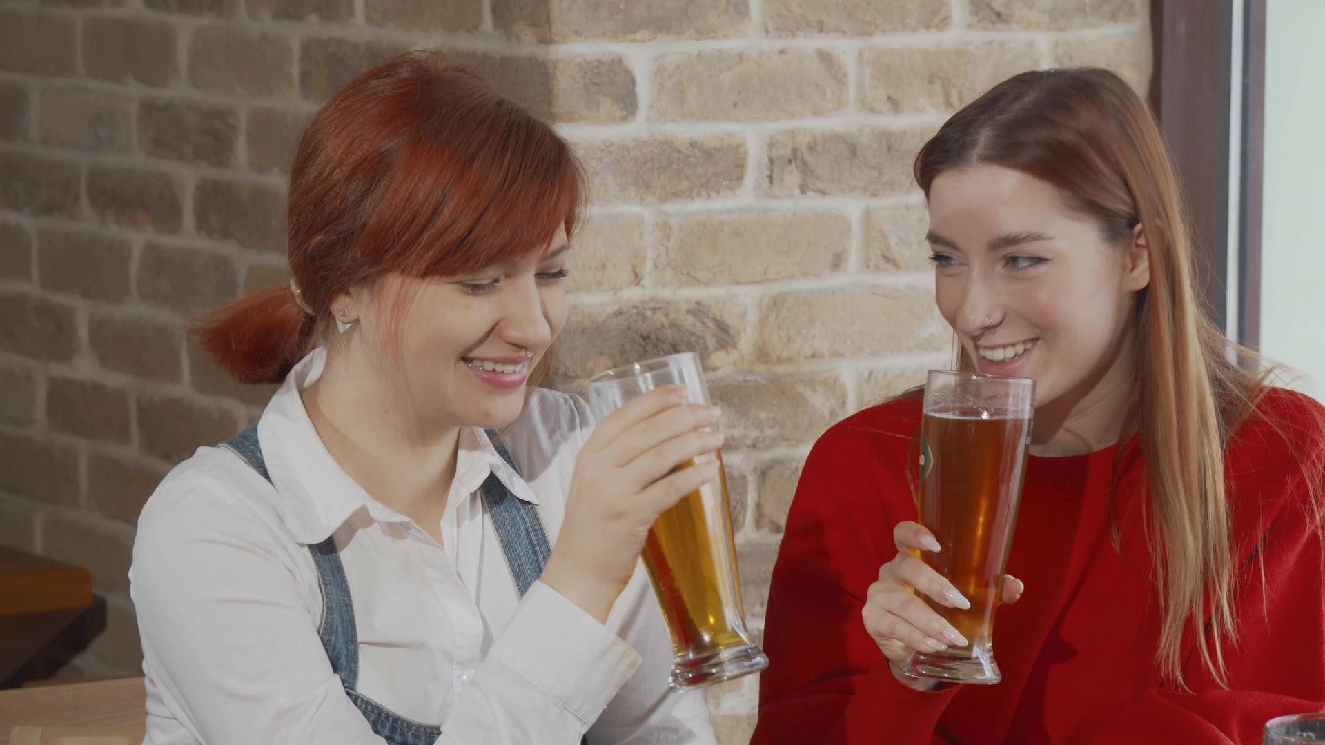 酒吧里有两个年轻女子在喝啤酒杯视频的预览图