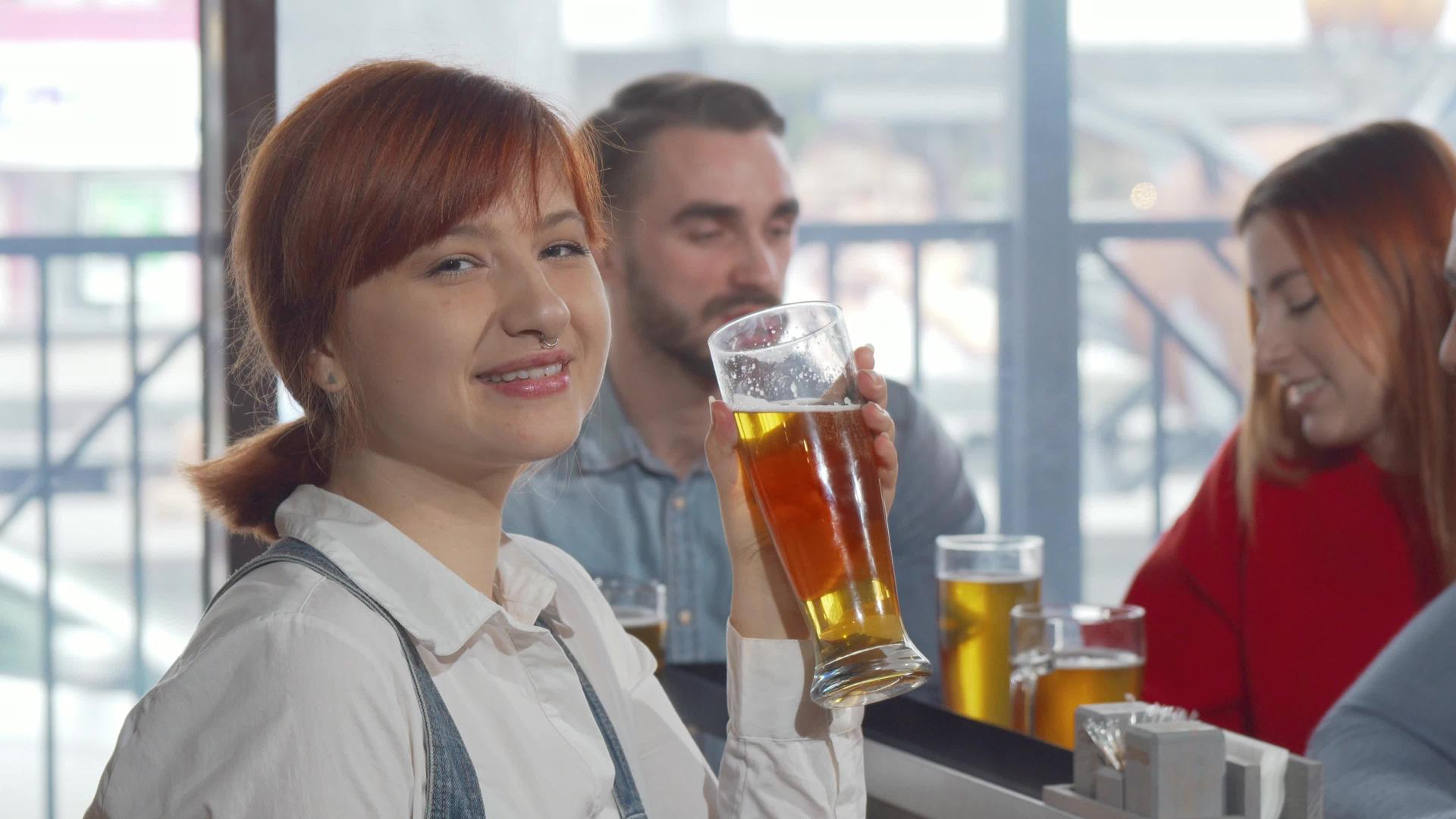 喝着美味的啤酒迷人的女人对着镜头微笑视频的预览图