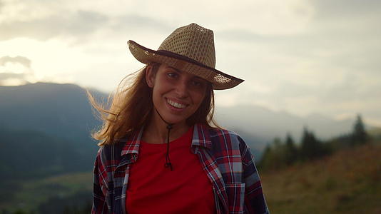 微笑的女人在山的肖像上看日落视频的预览图
