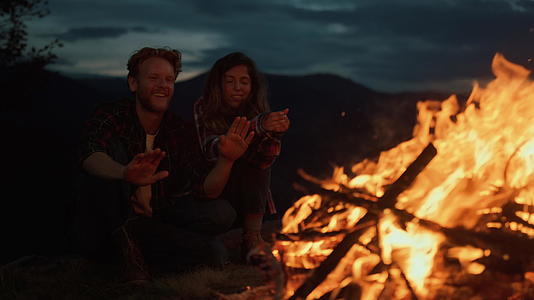 情侣温暖的手在夜间篝火特写上休息视频的预览图