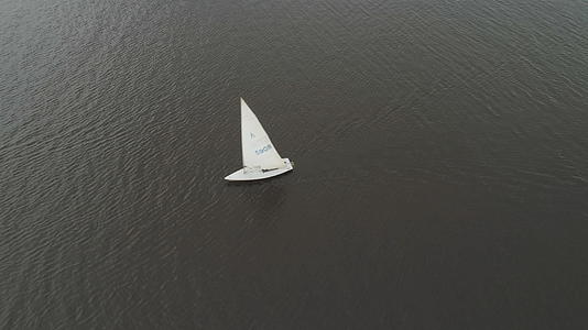 白色帆船从上到下垂直于海湾的空中视频的预览图