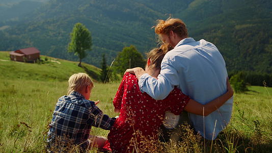 慈爱的父母拥抱坐在山上的儿子视频的预览图