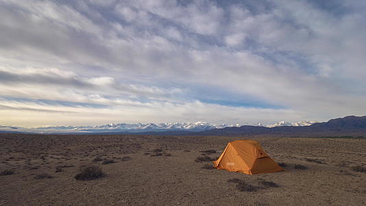 清晨的旅游帐篷和多彩的沙漠云以及雪山背景下的风雨时光视频的预览图
