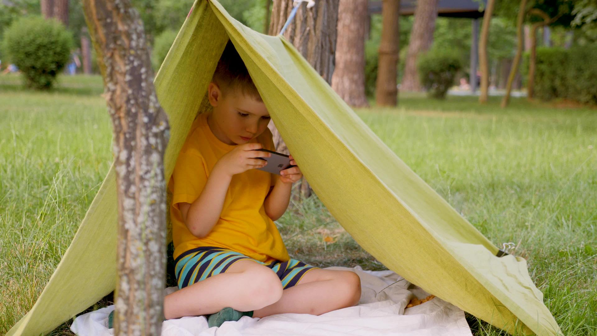 年轻的旅行者在帐篷里玩电子游戏男孩在做手工旅行的概念视频的预览图
