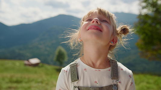 肖像小女孩看着天空站在草地上视频的预览图