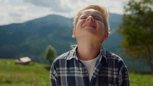 享受阳光的小男孩在夏日群山中仰望天空视频的预览图