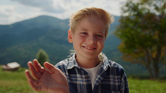 微笑的男孩在绿草地上挥手视频的预览图