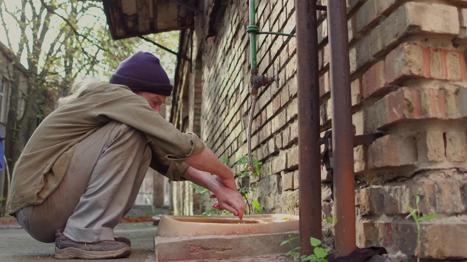 流浪汉在街上的旧水槽里洗手视频的预览图