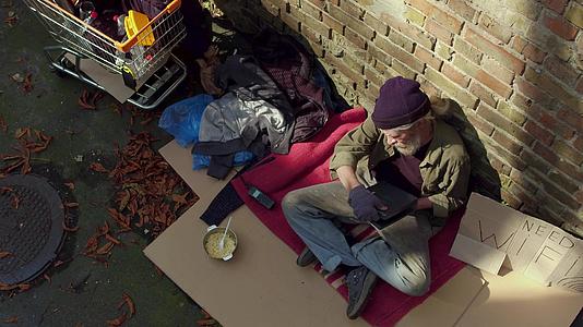 近距离看着无家可归的老人拿着笔记本电脑视频的预览图