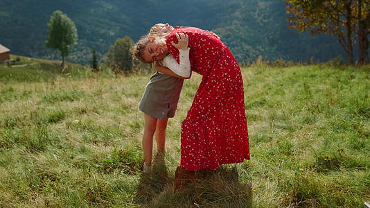 幸福的女人女儿拥抱在绿草上视频的预览图