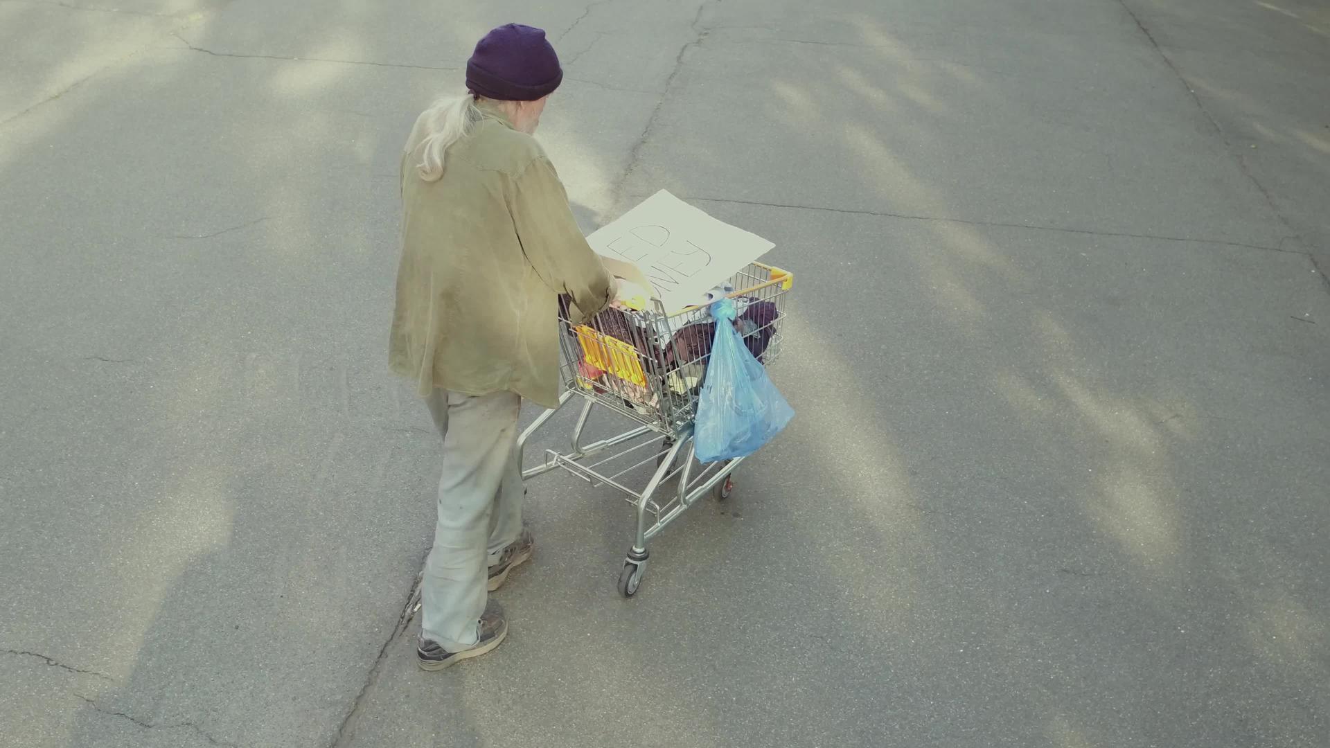 流浪老人推着购物车在街上靠近长凳于是视频的预览图