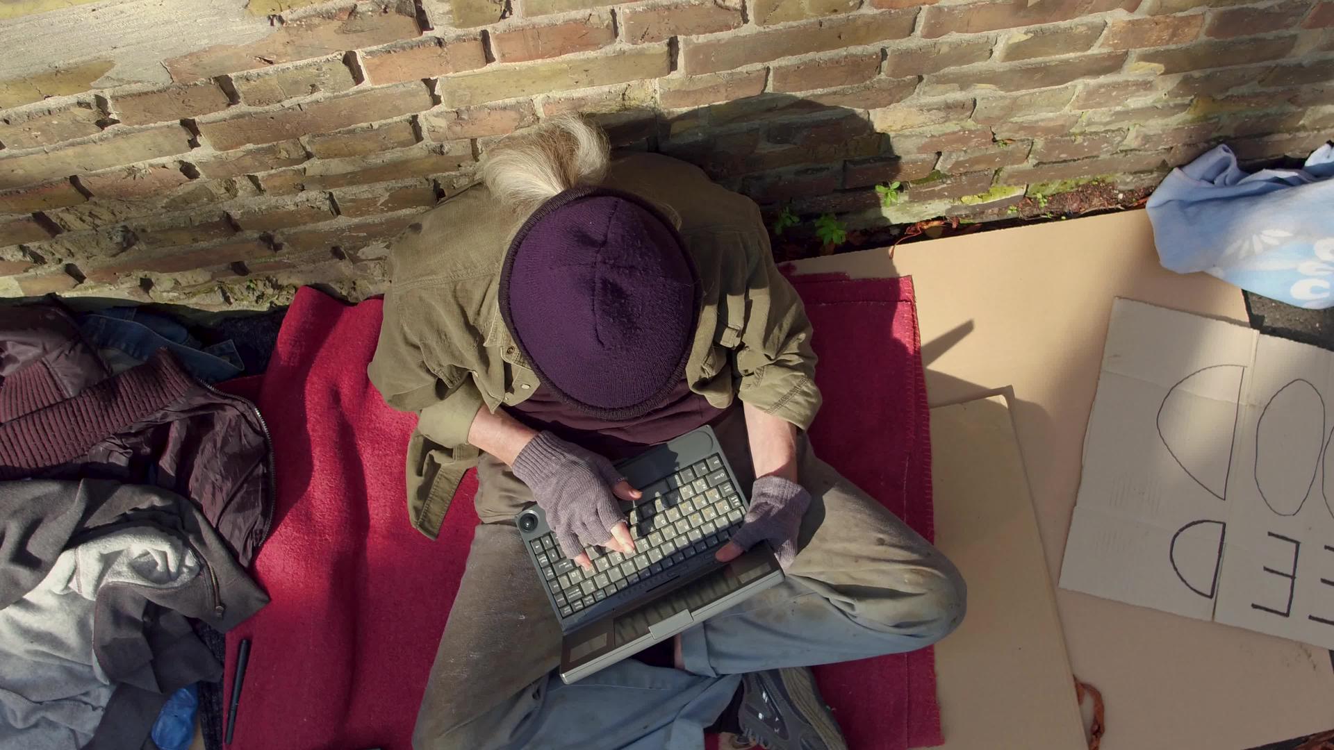 现代无家可归者使用笔记本电脑的顶部视图视频的预览图