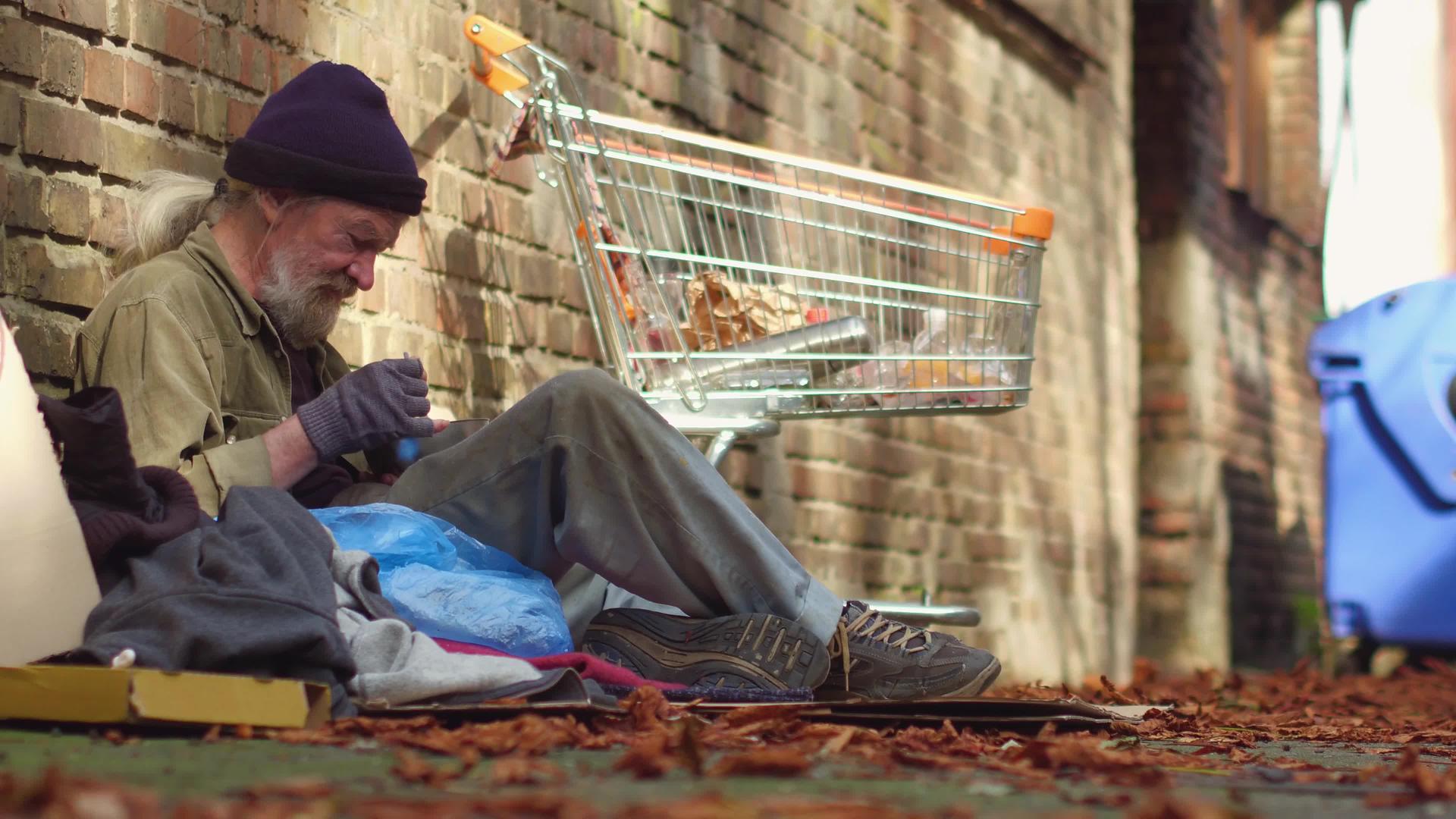无家可归者坐在街上的卡片店里吃饭视频的预览图