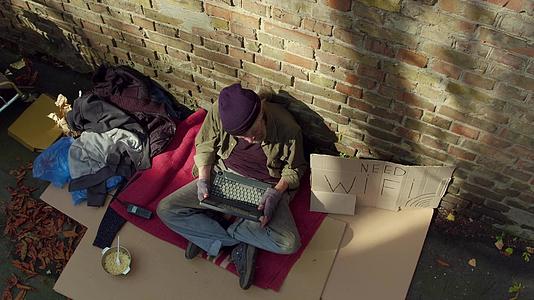 老无家可归男子手持笔记本电脑的场景视频的预览图