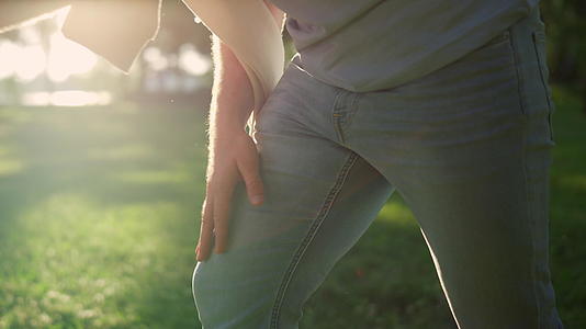 特写男子手拍腿在金色阳光公园视频的预览图
