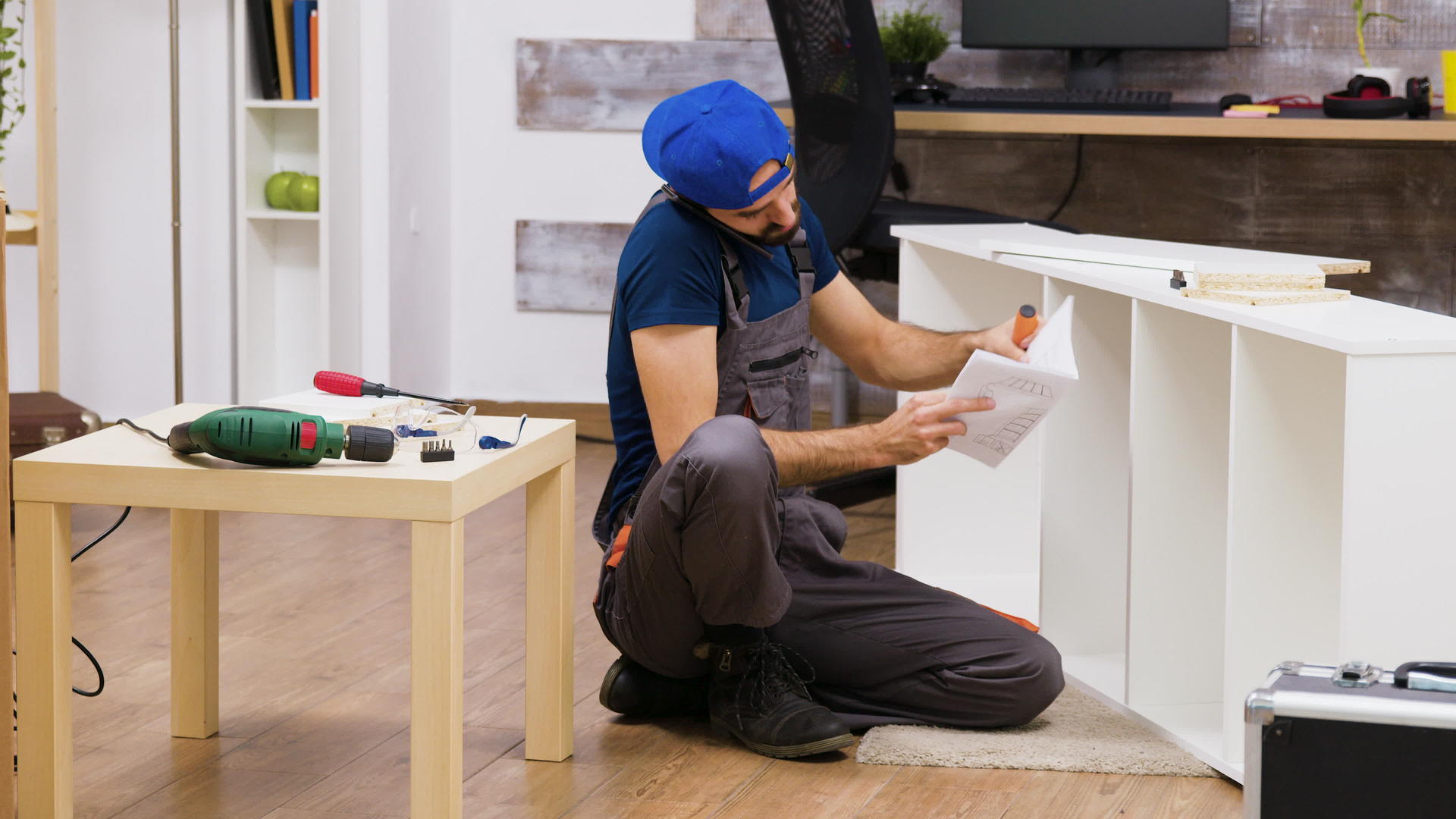 男性工人在组装白色家具时通过电话交谈视频的预览图