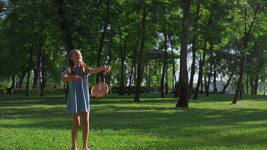 快乐的小女孩在城市公园里用球拍打毽子视频的预览图