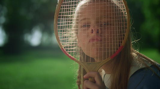 快乐女孩在夏季公园特写中用羽毛球拍做鬼脸视频的预览图