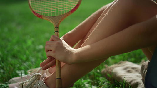 特写女孩腿手持羽毛球拍在公园里视频的预览图