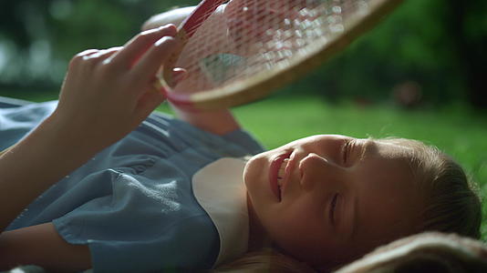 梦幻女孩特写的金色阳光躺在毯子上摸着球拍弦视频的预览图