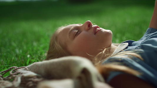 金发女孩微笑着躺在毯子上手牵手靠近绿色的田野视频的预览图