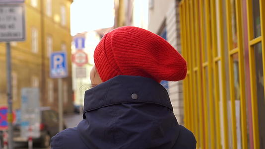 红帽女走在五颜六色的欧洲街道上视频的预览图