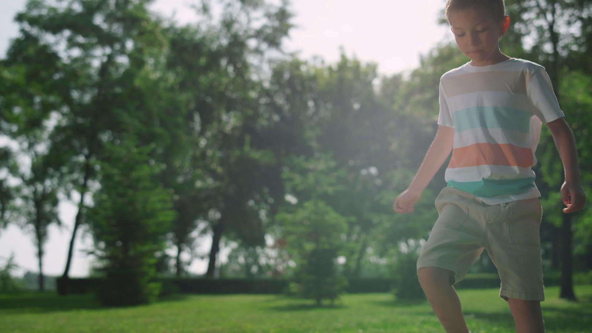 快乐的男孩在公园的阳光下踢足球视频的预览图