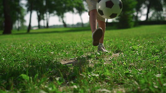 活跃的男孩在绿草上踢足球视频的预览图