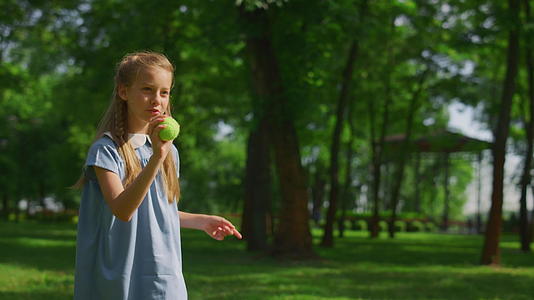少女训练在绿色公园近距离投掷球视频的预览图